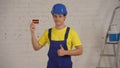 Medium shot of a young construction worker standing in the room under renovation with a credit card in his hand, giving Royalty Free Stock Photo