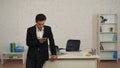 Medium shot of a young man in an office, holding a smartphone in hand, receiving a message, notification with bad news