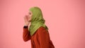 Medium side profile isolated photo capturing an attractive young woman wearing a hijab, veil. She looks sneaky and sly