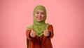 Medium-sized isolated photo capturing an attractive young woman wearing a hijab, veil. She is giving the thumbs up