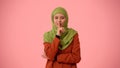 Medium-sized isolated photo capturing an attractive young woman wearing a hijab, veil. She looks sneaky and sly
