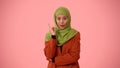 Medium-sized isolated photo capturing an attractive young woman wearing a hijab, veil. She raised her finger in the air