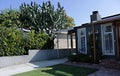 Medium-sized residential building with a concrete path to the main entrance with a green lawn in front of the house and large cact Royalty Free Stock Photo