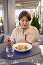 medium sized woman in peach fuzz dress eating cottage cheese pancakes with salmon and spinach in modern restaurant Royalty Free Stock Photo