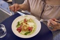 medium sized woman in peach fuzz dress eating cottage cheese pancakes with salmon and spinach in modern restaurant Royalty Free Stock Photo