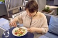 medium sized woman in peach fuzz dress eating cottage cheese pancakes with salmon and spinach in modern restaurant Royalty Free Stock Photo