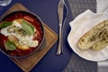 medium sized woman in peach fuzz dress eating Shakshouka in modern restaurant