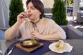 medium sized woman in peach fuzz dress eating Shakshouka in modern restaurant