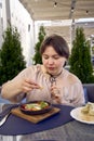 medium sized woman in peach fuzz dress eating Shakshouka in modern restaurant