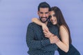 Medium studio copy space shot over violet lavender background of a beautiful heterosexual couple hugging and looking at