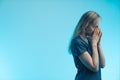Medium studio shot on blue background of a concerned worried european blonde female doctor with her hands folded near