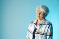 Medium studio shot of elderly gray-haired caucasian lady wearing flannel shirt and sadly looking away.