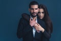 Medium studio shot over dark blue background of a sensual interracial couple wearing elegant clothes, woman hugging the Royalty Free Stock Photo