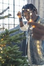 medium vertical shot of an Afro-American man with glasses holding lights in front of a Christmas tree Royalty Free Stock Photo