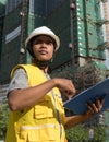 Medium vertical view Asian architectural engineer looking offscreen with background building Royalty Free Stock Photo