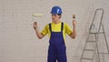 Medium video of a young construction worker standing in the room under renovation, choosing between a rolloer and a