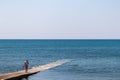 Medulin - Tourist woman walking on concrete pier in the waters of Adriatic Sea in coastal town Medulin, Istria peninsula, Croatia Royalty Free Stock Photo