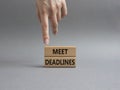 Meet Deadlines symbol. Concept word Meet Deadlines on wooden blocks. Beautiful grey background. Businessman hand. Business and Royalty Free Stock Photo