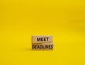 Meet Deadlines symbol. Concept word Meet Deadlines on wooden blocks. Beautiful yellowbackground. Business and Meet Deadlines Royalty Free Stock Photo