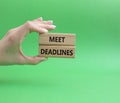 Meet Deadlines symbol. Concept word Meet Deadlines on wooden blocks. Businessman hand. Beautiful green background. Business and Royalty Free Stock Photo