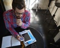 Meet me for coffee...a young man sitting at a table in a cafe with his cellphone, digital tablet and diary in front of Royalty Free Stock Photo