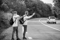 Meet New People. Looking for transport. twins walking along road. stop car with thumb up gesture. hitchhiking and Royalty Free Stock Photo