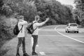 Meet New People. Looking for transport. twins walking along road. stop car with thumb up gesture. hitchhiking and Royalty Free Stock Photo