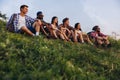 Meet sunset. Group of friends, young men and women walking, strolling together during picnic in summer forest, meadow Royalty Free Stock Photo