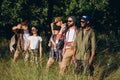 Meet sunset. Group of friends, young men and women walking, strolling together during picnic in summer forest, meadow Royalty Free Stock Photo