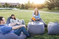 Meeting friends in the backyard of the house or in open air cafe. A man and women are sitting on frameless chairs on the lawn and Royalty Free Stock Photo