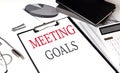 MEETING GOALS text on paper clipboard with chart and notebook on withe background