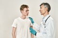 Meeting at hospital. Mature professional doctor in medical uniform and blue sterile gloves speaking with worried young Royalty Free Stock Photo