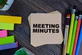 Meeting Minutes write on sticky notes isolated on Wooden Table