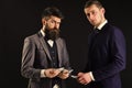 Meeting of reputable businessmen, black background. Man with beard on serious face counting money, pay to partner Royalty Free Stock Photo