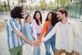 Meeting of smiling young adult people, men and women stacking hands showing unity or support enjoying together outside Royalty Free Stock Photo