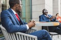 Meeting of two long-time friends of black African American businessman in suits outdoors in a summer city cafe Royalty Free Stock Photo