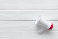 Megaphone for advertising and announcement on white wooden background top view copyspace