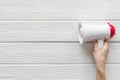 Megaphone in hand for advertising and announcement on white wooden background top view copyspace