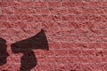 Megaphone speaking announcing man shadow against red brick wall background or wallpaper