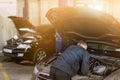 Mehanic doing check-up under opened car hood. Tools over dirty motor room. Car service and maintenance.Toned Royalty Free Stock Photo