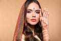 Mehendi. Portrait of beautiful indian girl in saree isolated on beige. Young hindu woman model with kundan golden jewelry set. Royalty Free Stock Photo