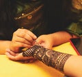 An artist performing mehandi or henna design on female hand.