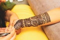 An artist performing mehandi or henna design on female hand.