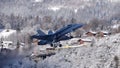 Armed Fighter Jet Takes Off on Sunny Winter Day with Snowy Mountains Background