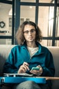 Melancholic dark-haired guy sitting on grey couch with guitar