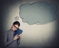 Melancholic student girl holding a textbook and wearing eyeglasses, looking down pensive. Blank thought bubble comes out of her Royalty Free Stock Photo