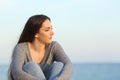 Melancholic woman looks away on the beach