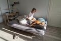 Melancholy pensive woman middle age sits in bedroom on bed and petting dog to get rid of depression Royalty Free Stock Photo