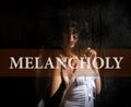 Melancholy written on virtual screen. hand of young woman melancholy and sad at the window in the rain. Royalty Free Stock Photo