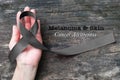 Melanoma and skin cancer black awareness ribbon on human helping hand old aged background Royalty Free Stock Photo